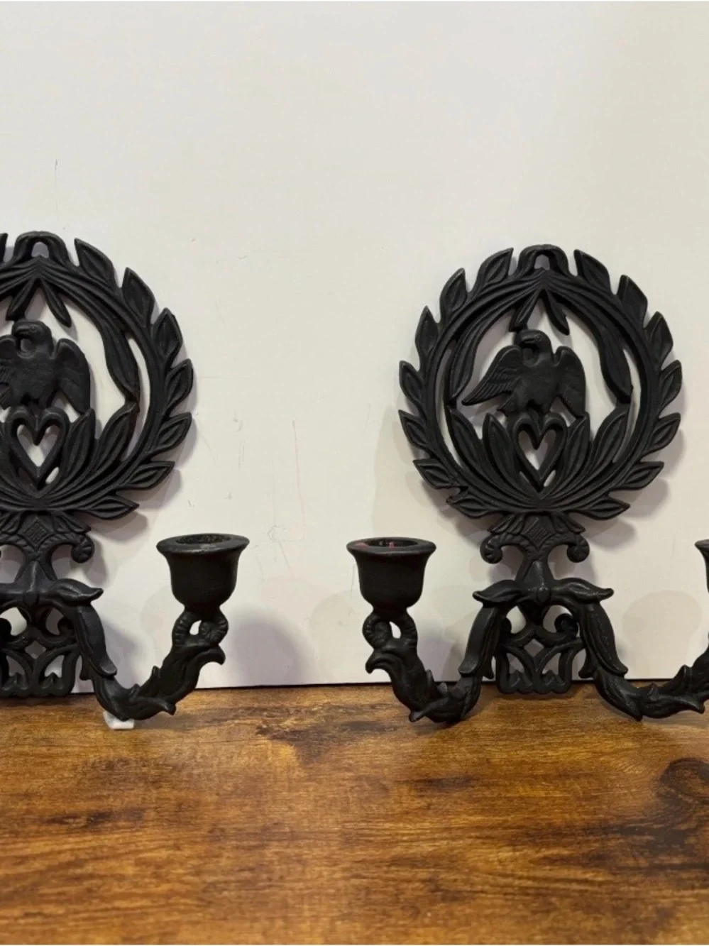 A pair of vintage cast iron wall sconces with eagle and laurel wreath motif